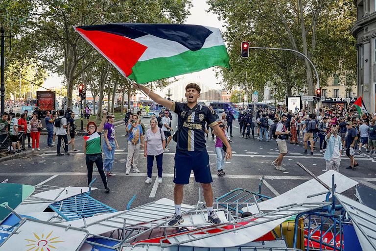 Un joven en primer plano ondea una bandera palestina.