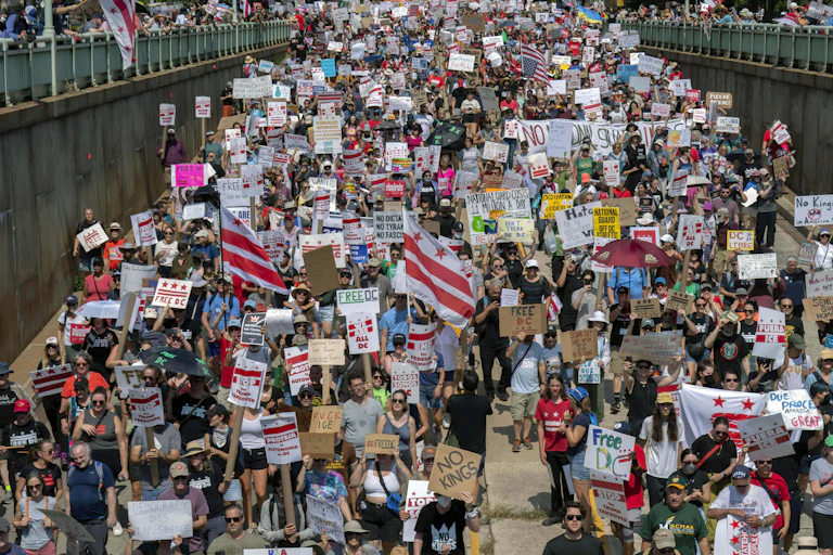 Aerial view of a crowd on an underpass, holding signs, including many reading 'Free DC'