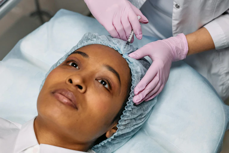 A woman lays down and has botox injected into her forehead