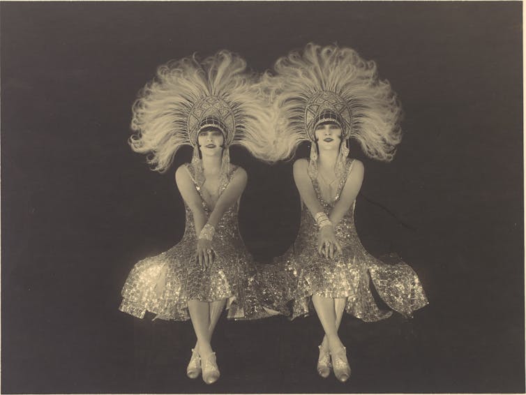 Two women wearing sequinned, feathered headdresses.