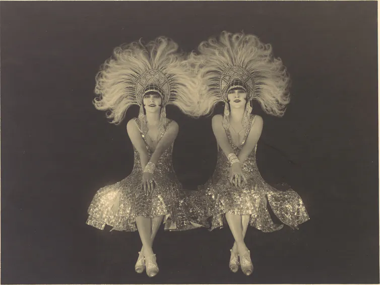 Two women wearing sequinned, feathered headdresses.