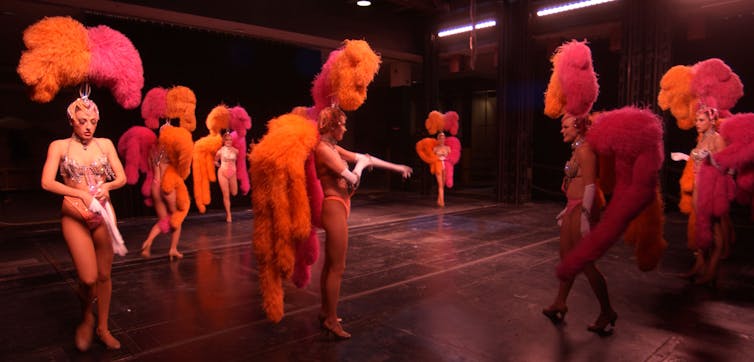 Showgirls in orange and pink feathers.