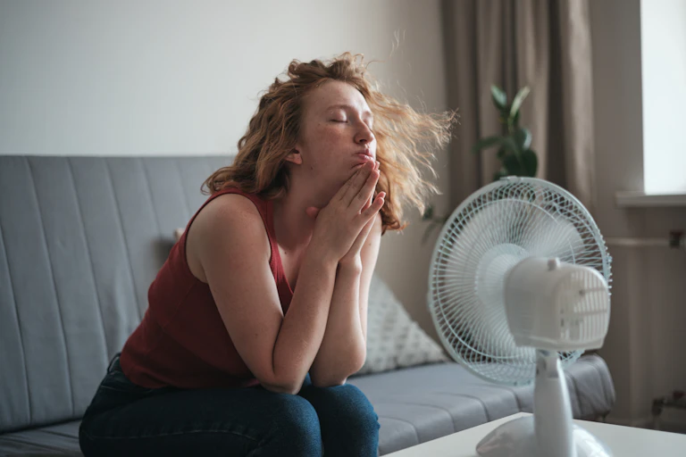 Woman sits in front of fan in her hot home