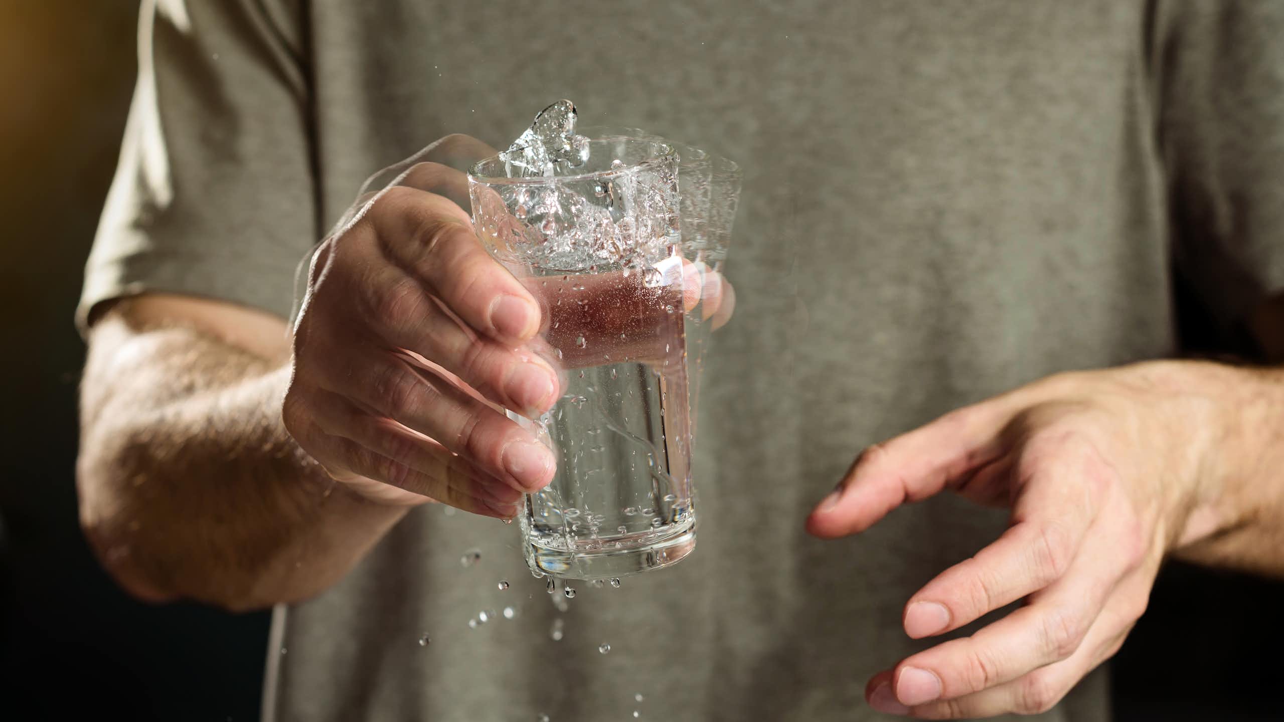 Un hombre sujeta un vaso con temblor en su mano