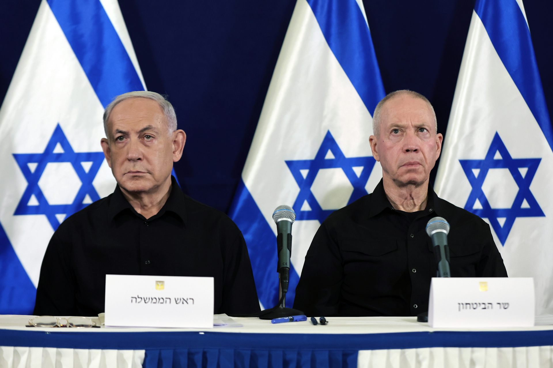 Israel's prime minister, Benjamin Netanyahu, and defence minister, Yoav Gallant, sit at a desk in front of Israeli flags.