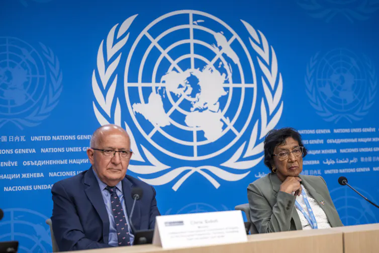 Navi Pillay, chair of the UN commission on Palestine (right), and Chris Sidoti, a member of the commission, sit at a desk in front of the United Nations logo.