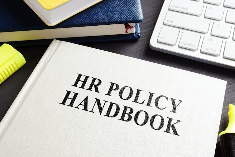 HR policy manual on a desk beside a computer keyboard