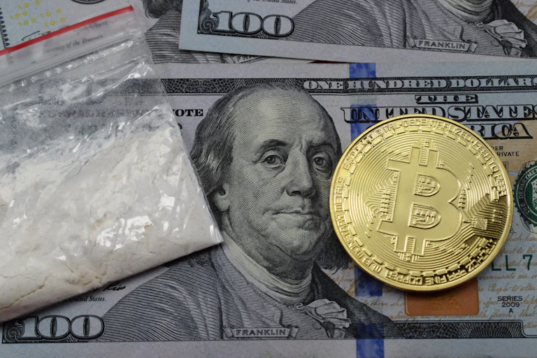 Billet de 100 dollars, jeton de Bitcoin et sachet de cocaïne.