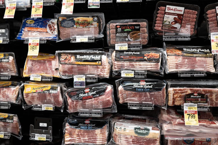 packages of bacon and other meat are on display in a grocery store