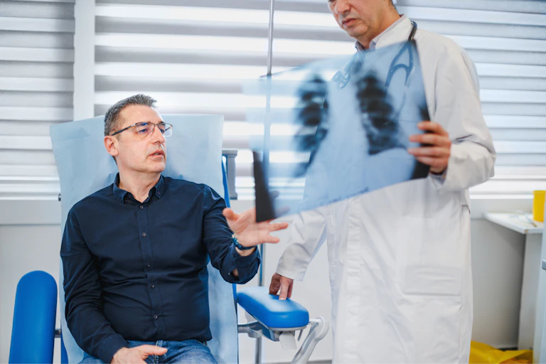 Man in medical clinic looking at chest X-ray with doctor