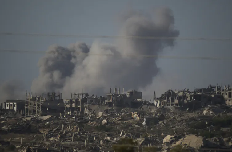 Smoke rises from the rubble of a city.