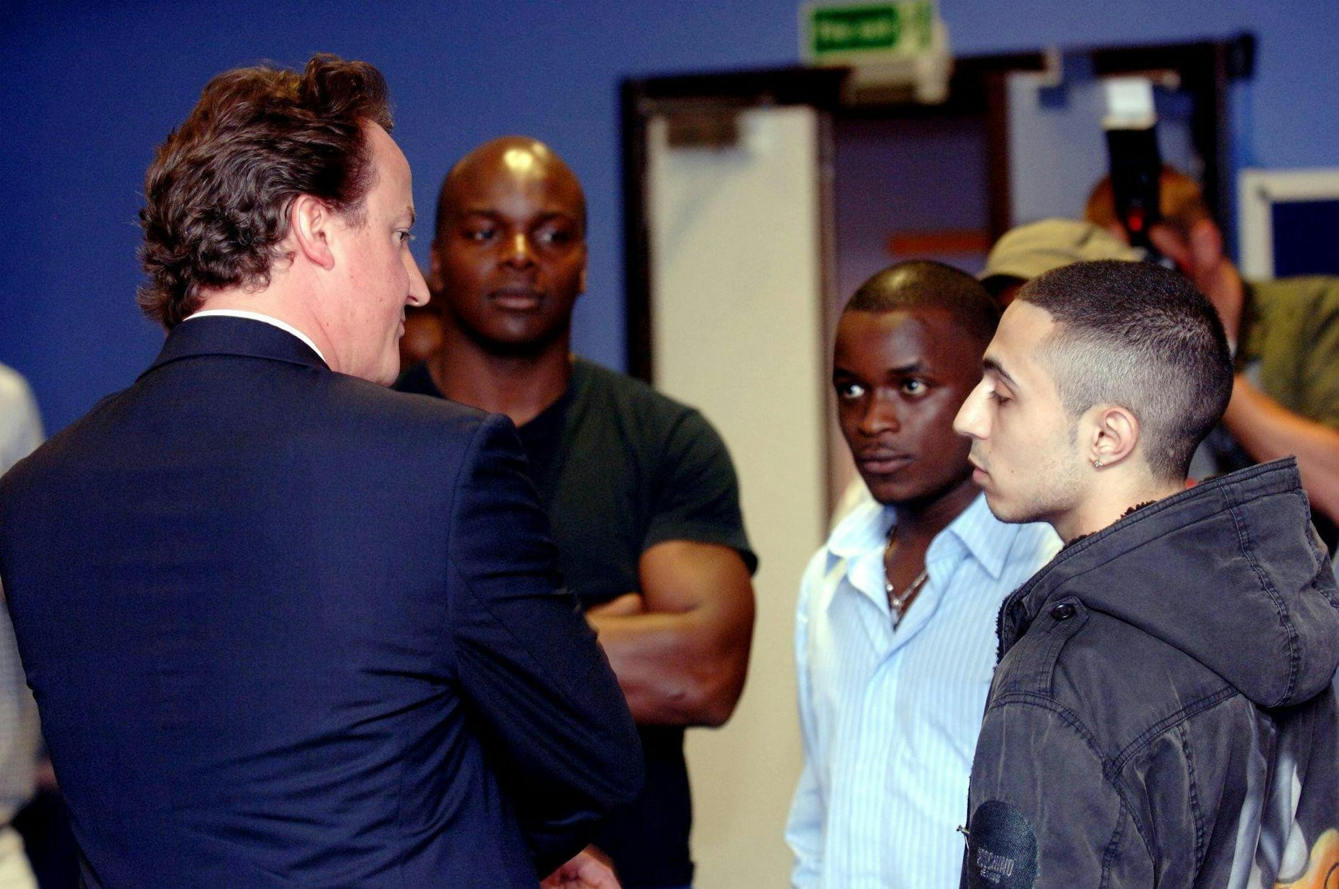 David Cameron talking to two young men.