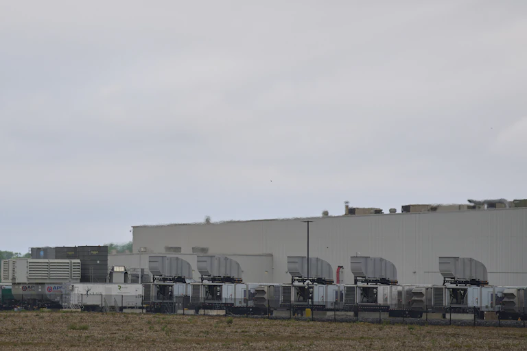 Large engines are lined up outside a large low building.