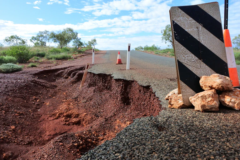 close up of washed out road with warning sign.