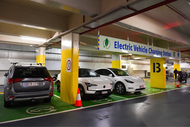 Cars are lined up at an electric vehicle charging station.