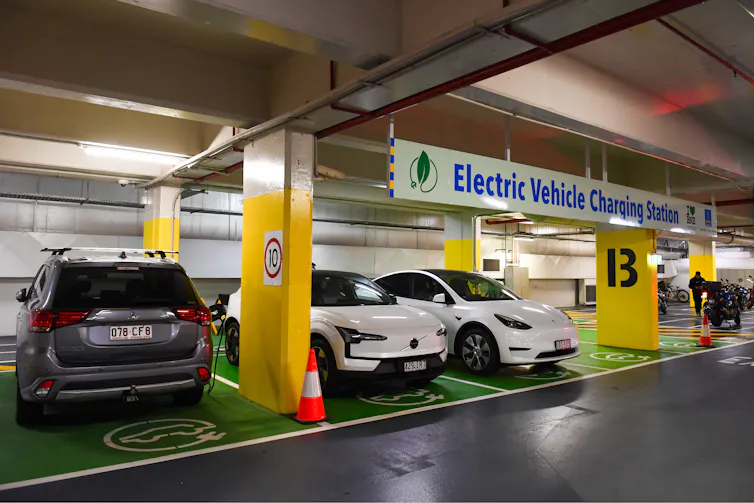 Cars are lined up at an electric vehicle charging station.