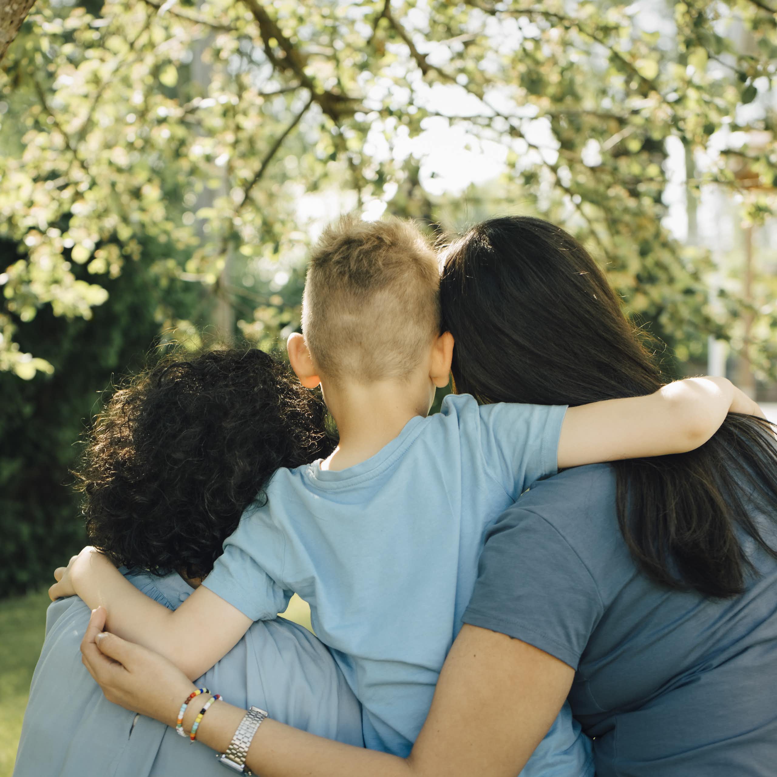 Two mums and their son, embracing, seen from the back