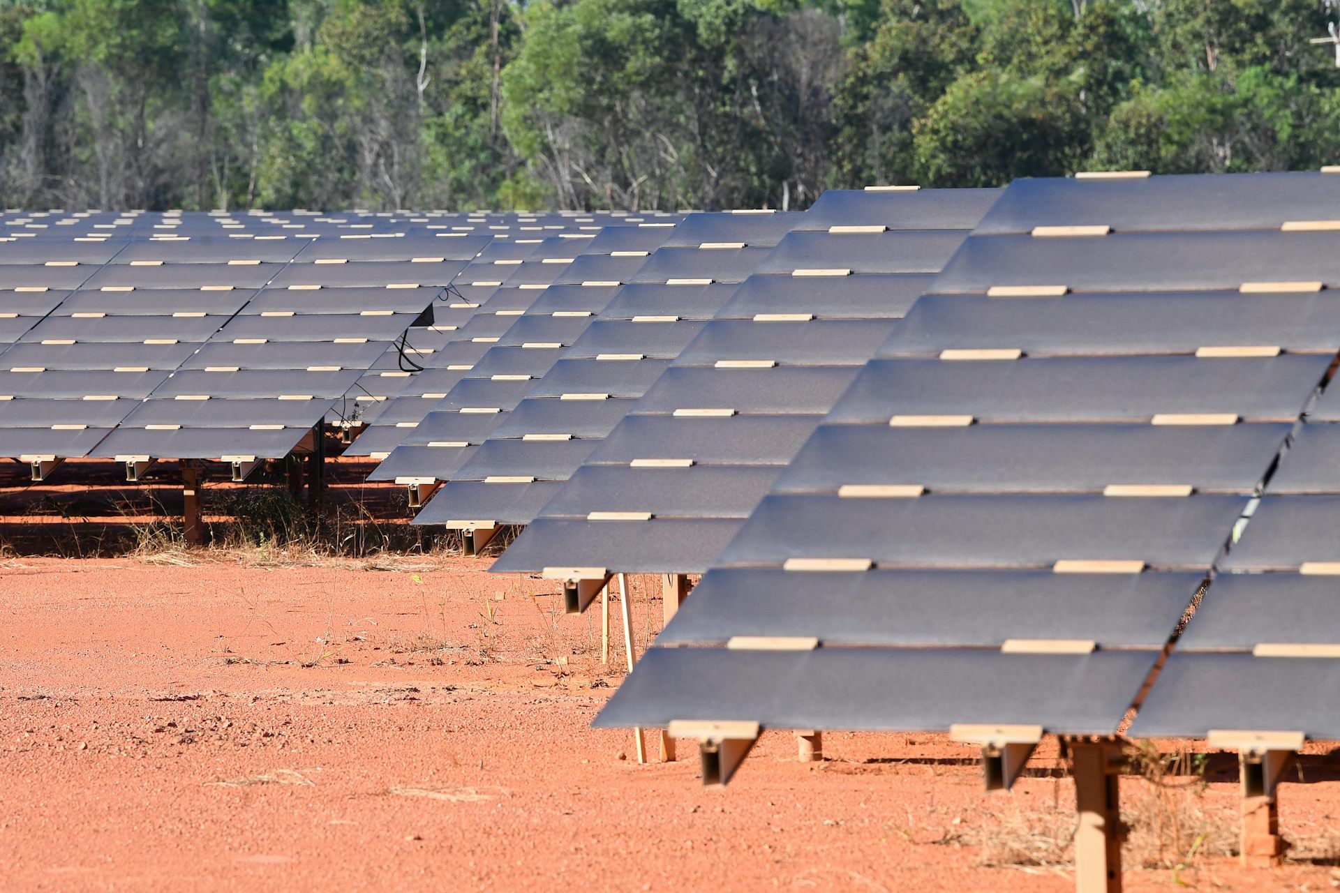 solar farm in desert, panels and red dirt.