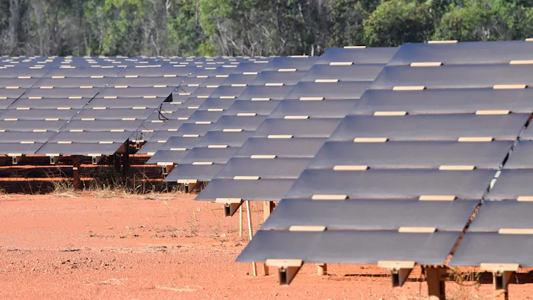 solar farm in desert, panels and red dirt.