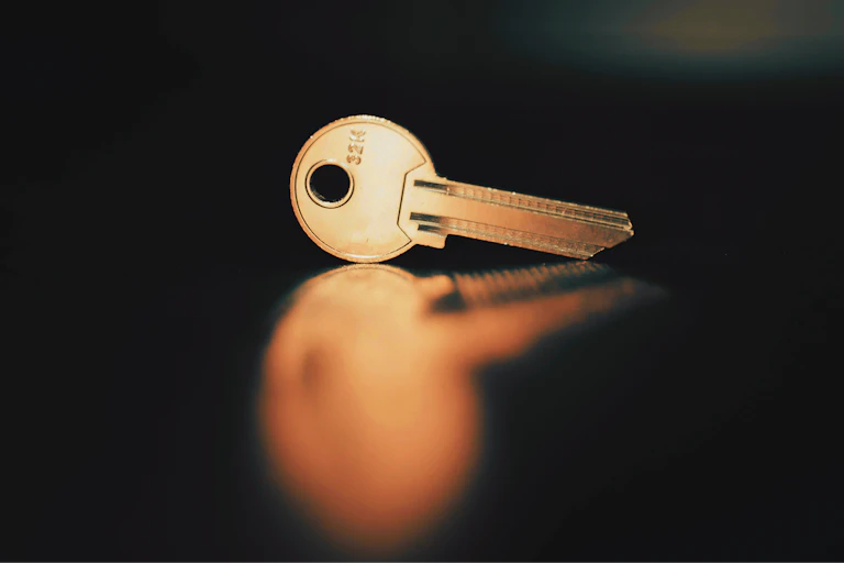 A shiny key on a reflective black surface.