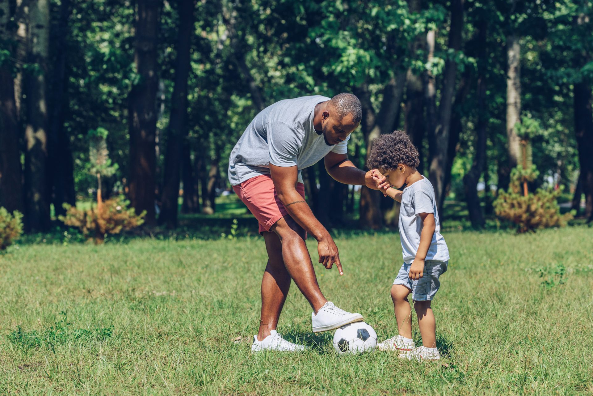 Un père joue au foot avec son enfant.