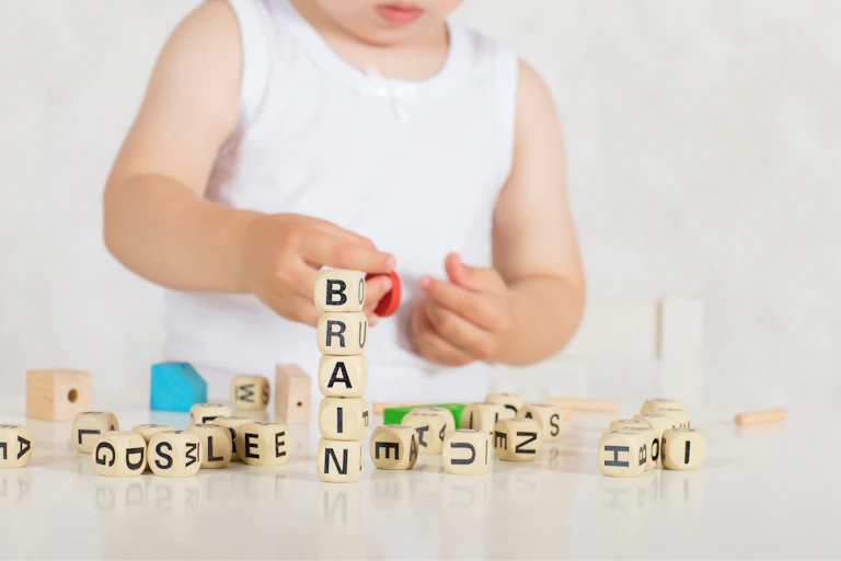 Un très jeune enfant joue avec des cubes sur lesquels figurent des lettres en majuscules.