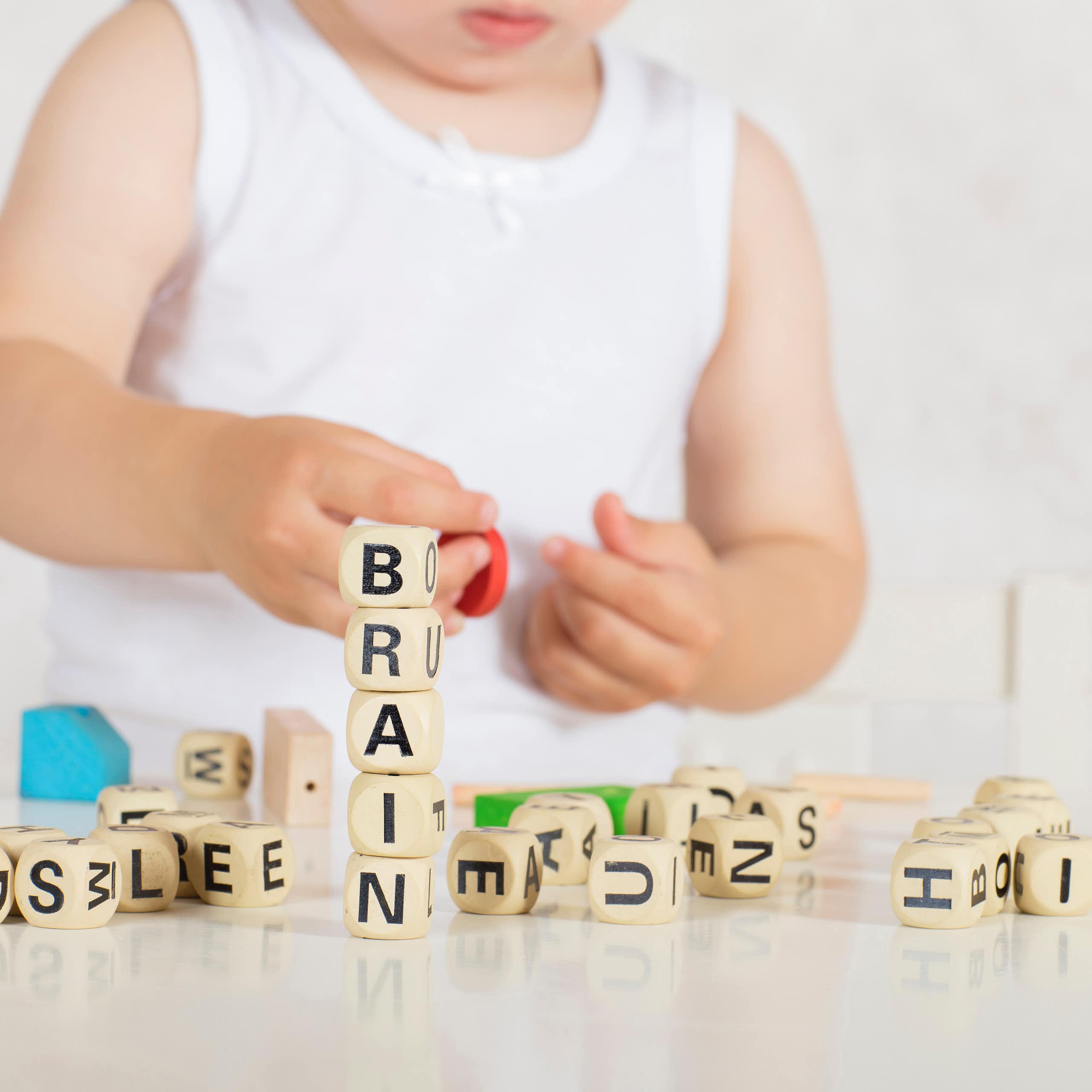 Un très jeune enfant joue avec des cubes sur lesquels figurent des lettres en majuscules.