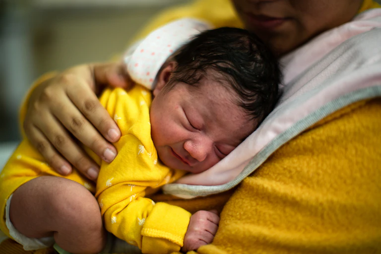 Closeup of newborn held against mother's chest