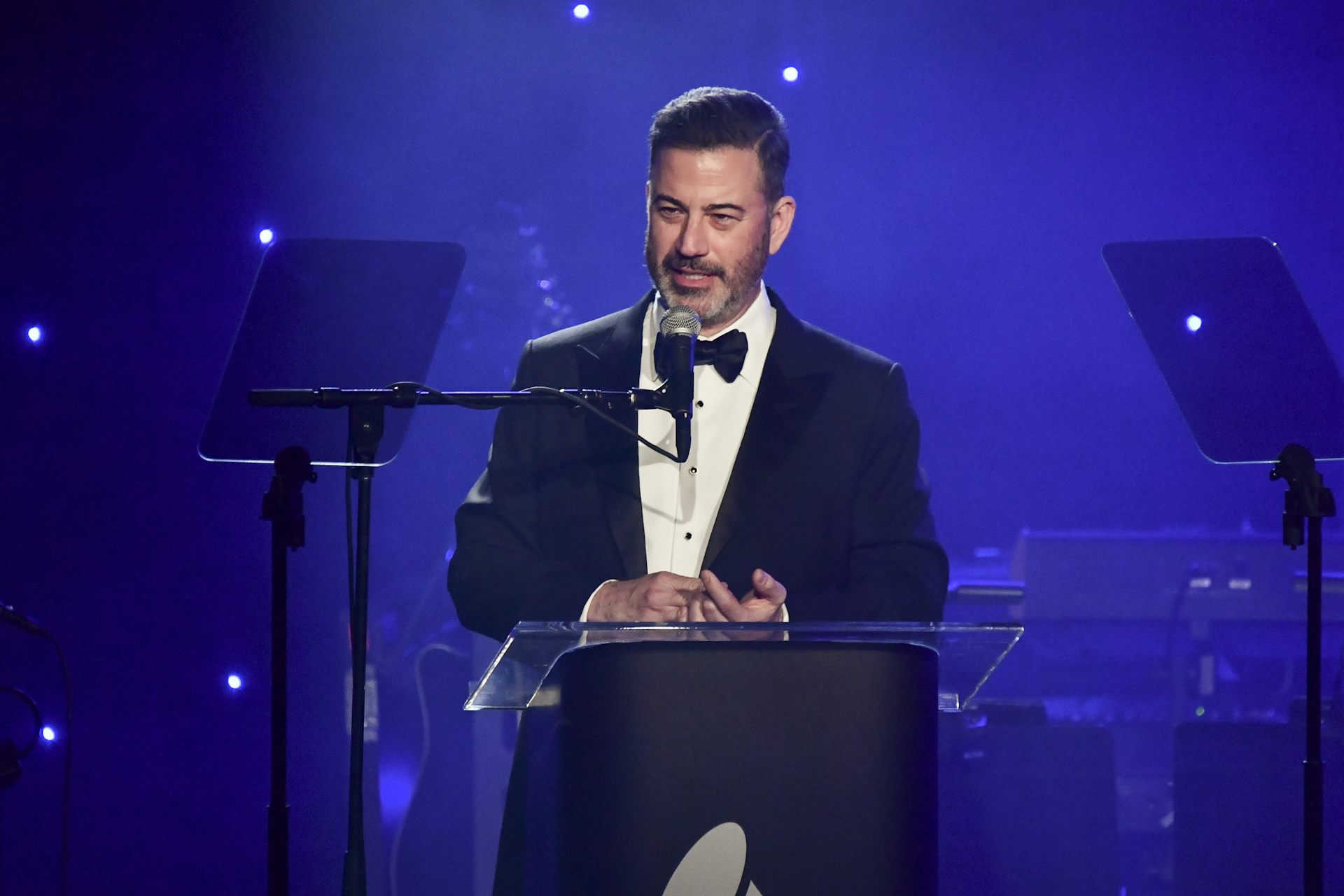 A white man in a suit speaks from behind a podium