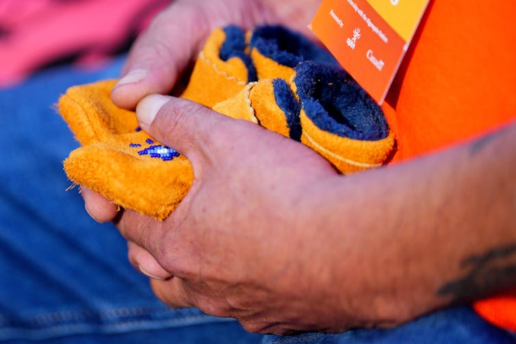 La persona tiene un par de mocasines infantiles en la ceremonia