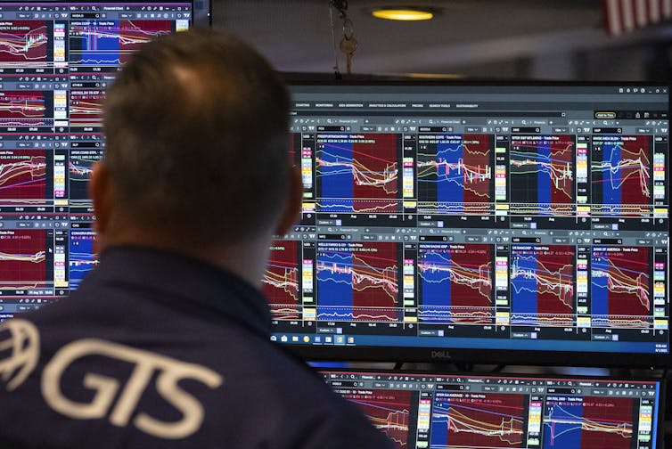 El hombre visto desde atrás, observa pantallas que muestran los precios del mercado de valores