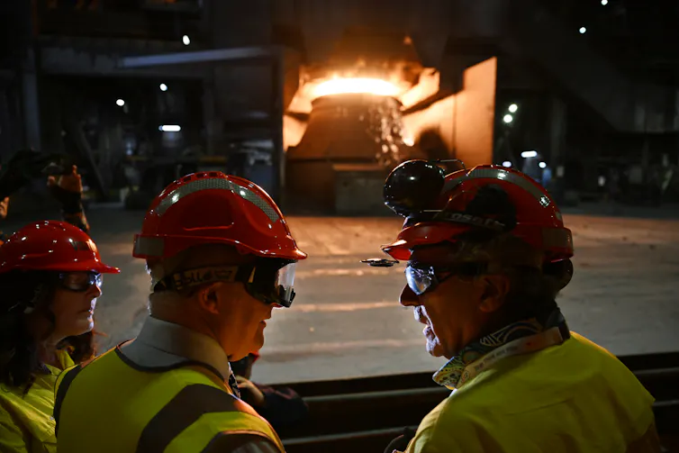men in hard hats in front of an industrial furnace