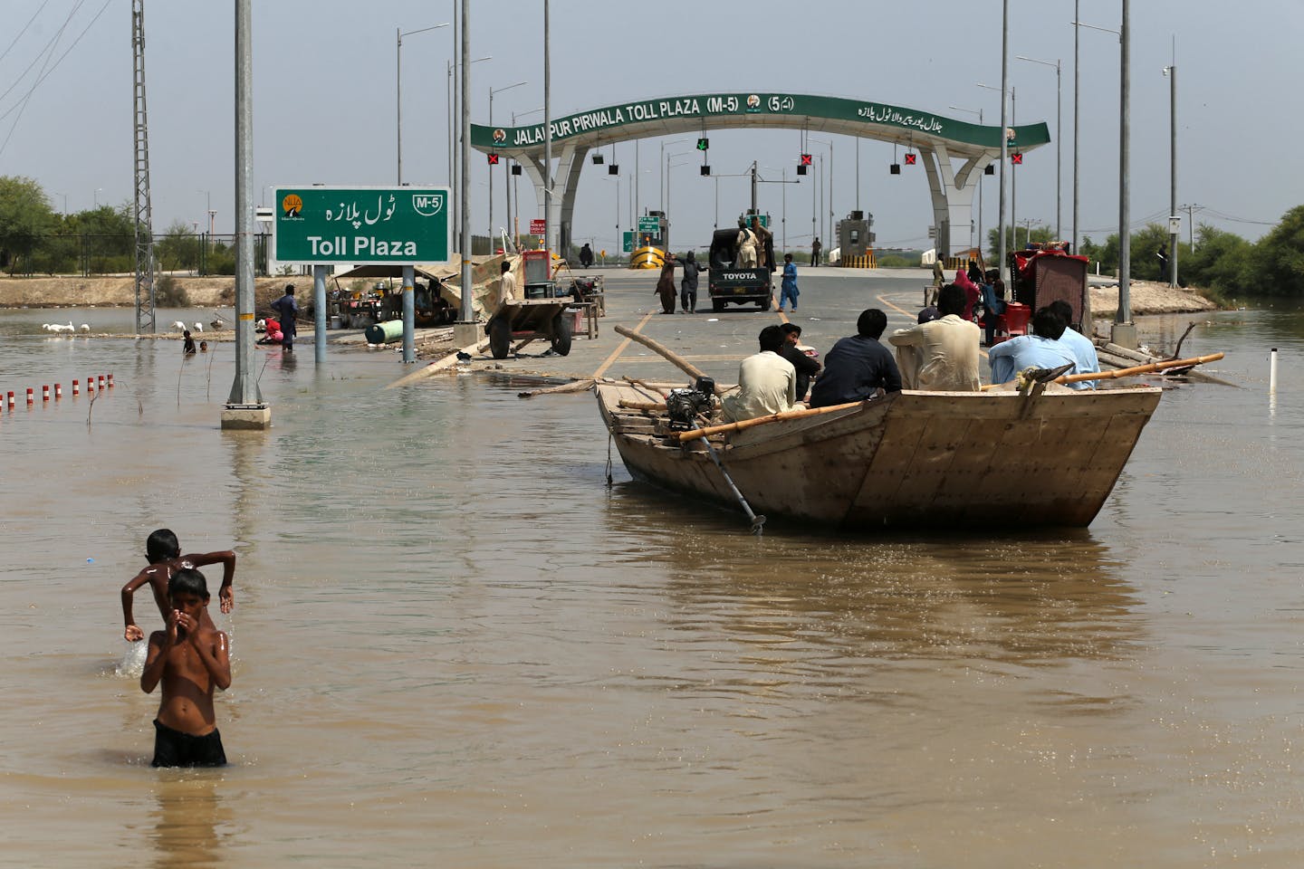 people on a boat on a flooded motorway in Pakistan.