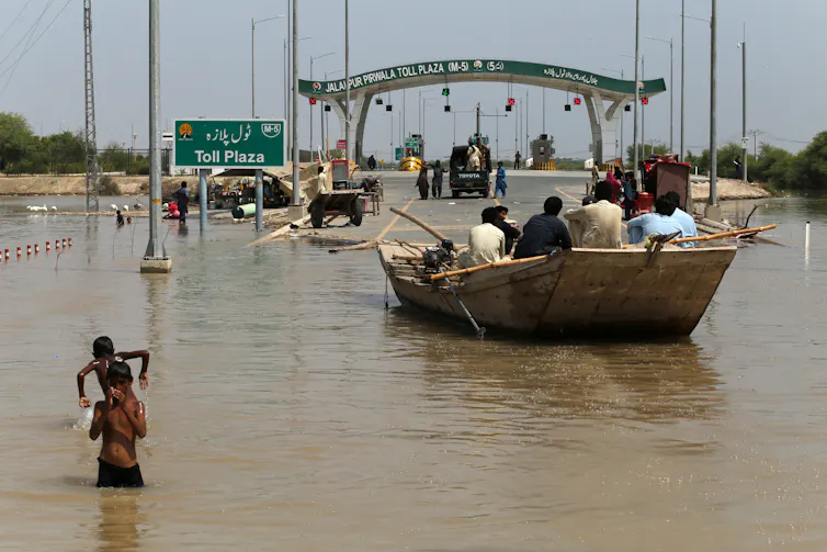 people on a boat on a flooded motorway in Pakistan.