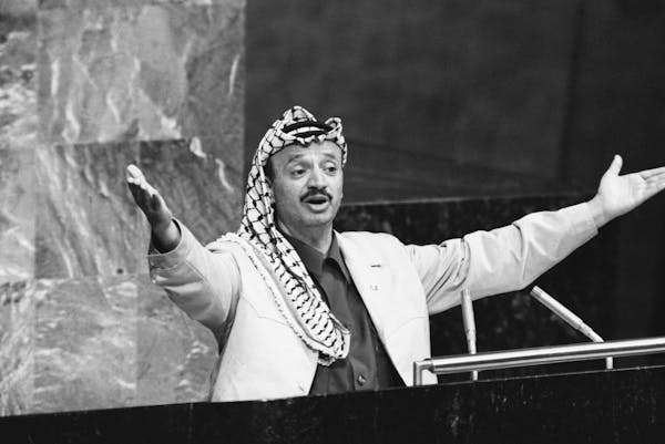 A man throws out his arms to make a point while he stands at a lectern.