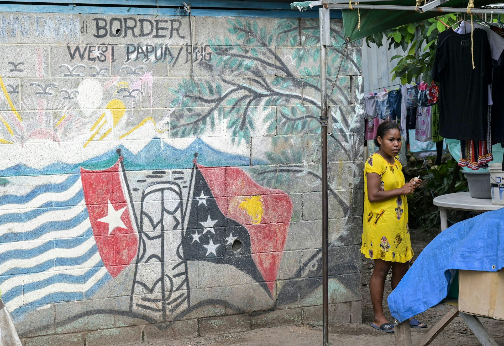 Woman stands beside wall with flags mural