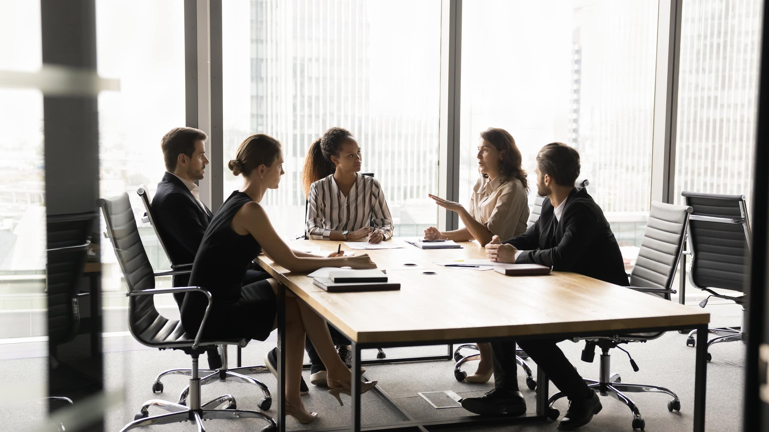 A group of people talk in a meeting room.