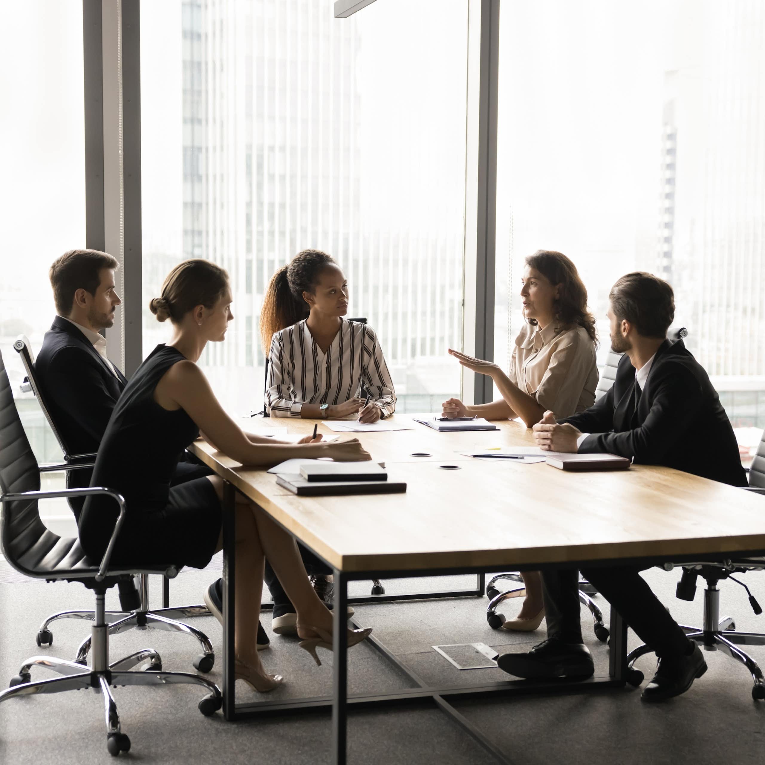 A group of people talk in a meeting room.