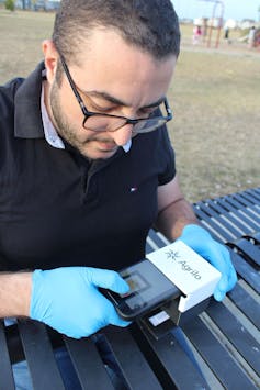 Un hombre que sostiene un pequeño dispositivo electrónico marcado Agrilo.