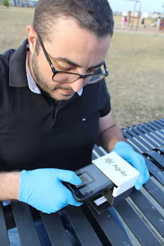 A man holding a small electronic device labeled Agrilo.
