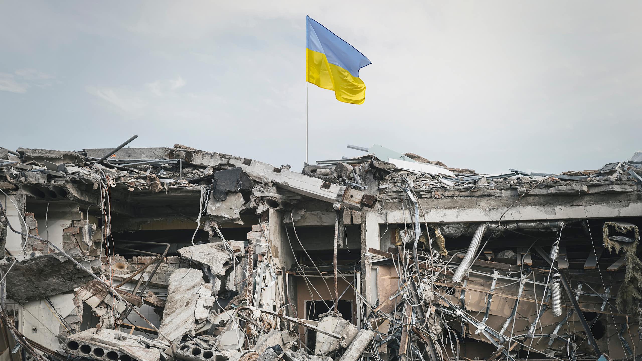 urban rubble with a ukrainian flag flying above it
