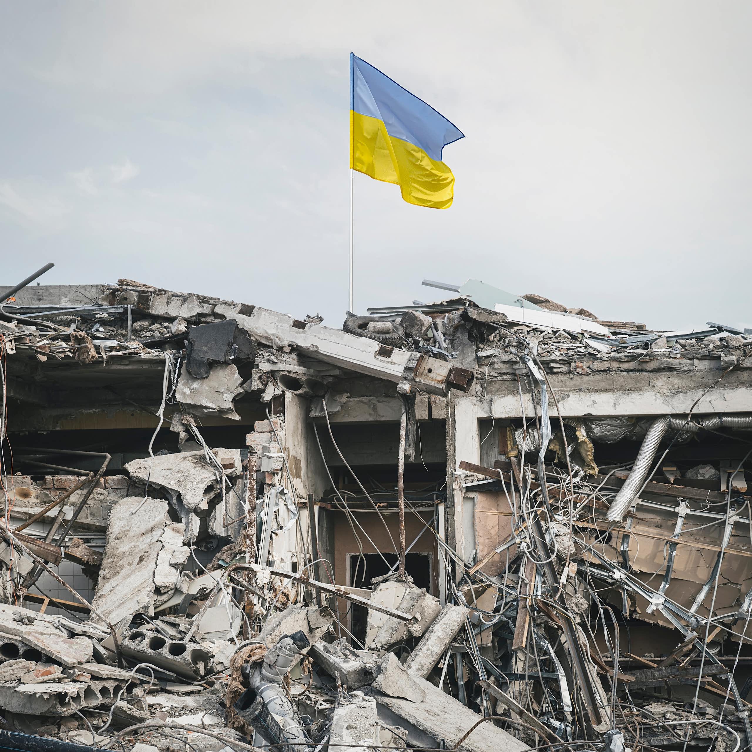 urban rubble with a ukrainian flag flying above it