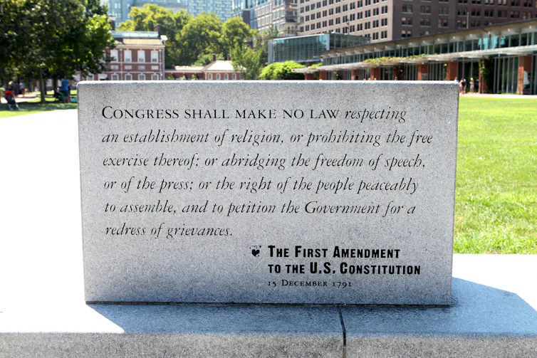 A small monument made out of marble has the First Amendment to the US Constitution printed on it.