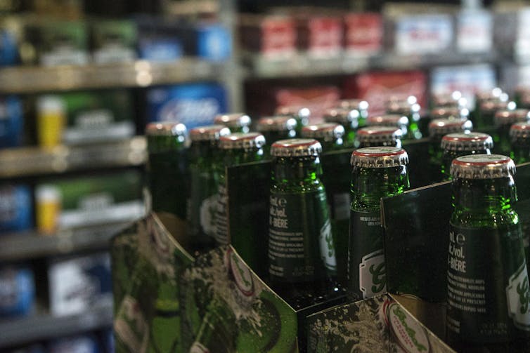 Beer bottles in foreground with shelves of beer cases out of focus in th background.