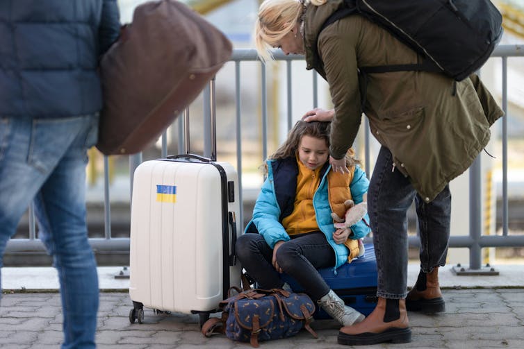 A man, woman and child are carrying their suitcases and traveling.