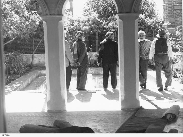 Five Islamic men can be seen near the pool.