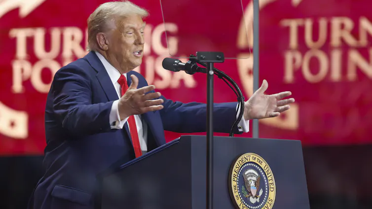 Donald Trump holds out his arms while speaking at a lectern at a Truning Point event September 21 2025.