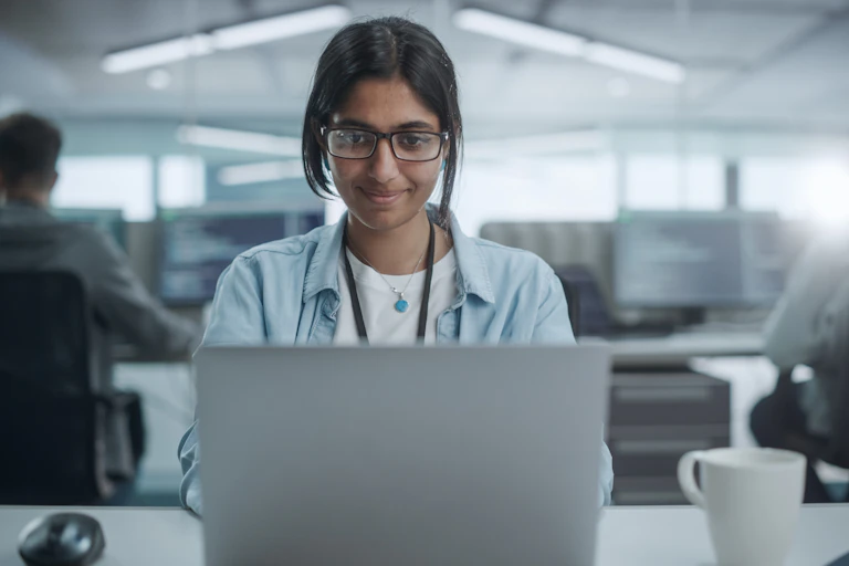 young female indian software developer sitting working on a laptop