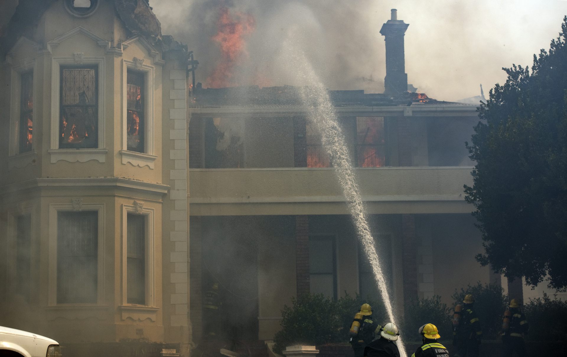 A jet of water aimed at a building, with flames and smoke visible