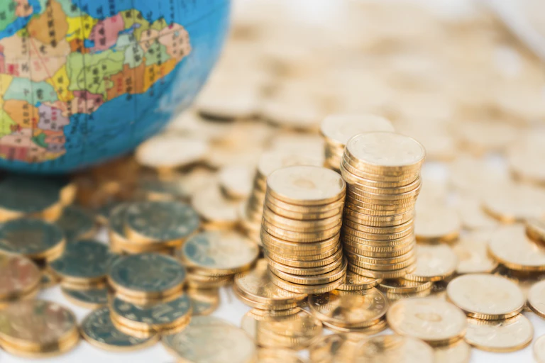 Coins scattered and piled next to a globe with map of Africa on it